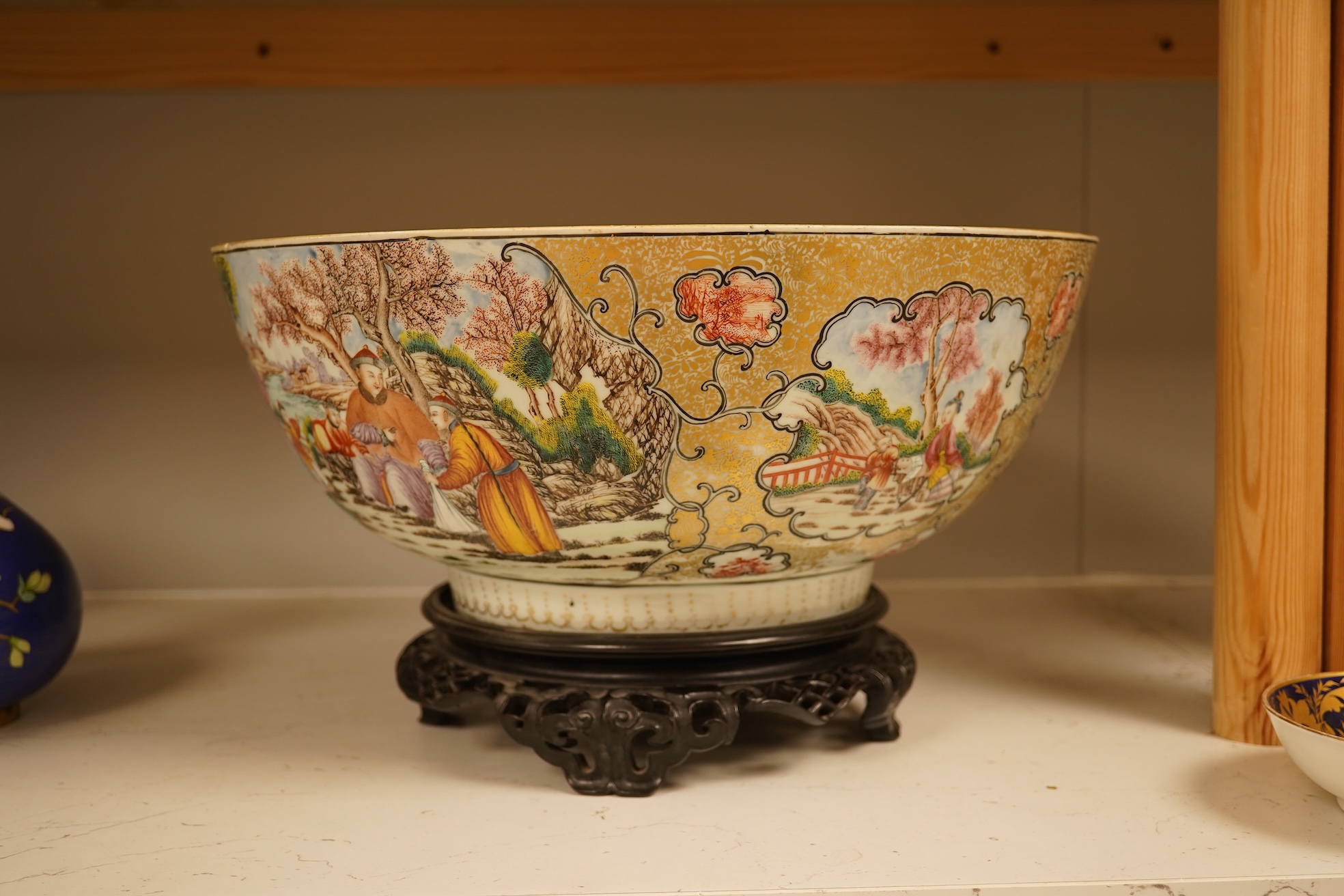 An 18th century Chinese famille rose figural bowl, on wooden stand, 34cm diameter.